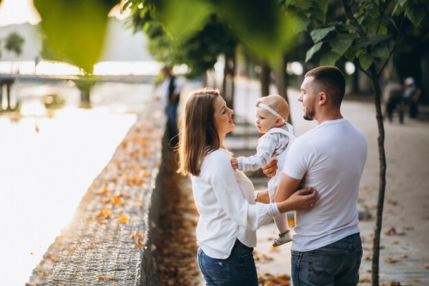 Familia joven con su pequeña hija en el parque otoño