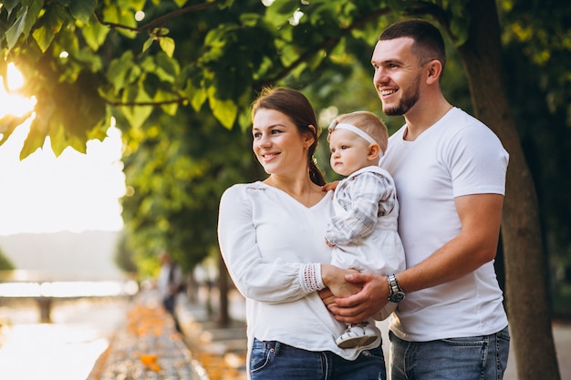 Familia joven con su pequeña hija en el parque otoño