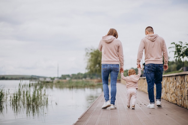 Familia joven con su pequeño hijo bebé en el parque junto al lago