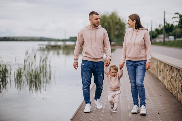 Familia joven con su pequeño hijo bebé en el parque junto al lago