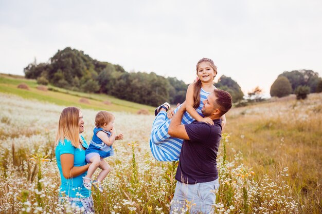 La familia juega con los niños en el campo con flores blancas