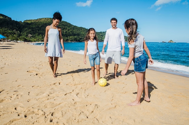 Familia jugando con balón en la playa