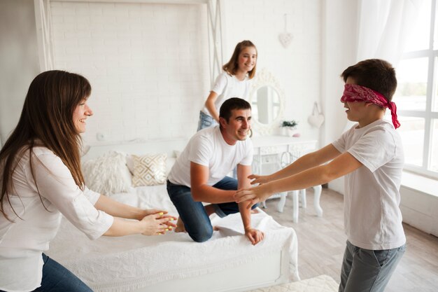 Familia juguetona jugando el juego de los ciegos en el dormitorio