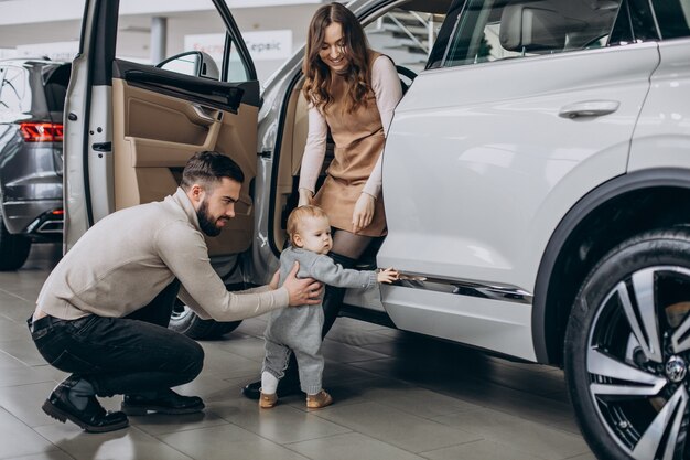 Familia con linda hija eligiendo un coche en una sala de exposición de coches