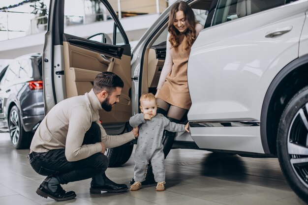 Familia con linda hija eligiendo un coche en una sala de exposición de coches