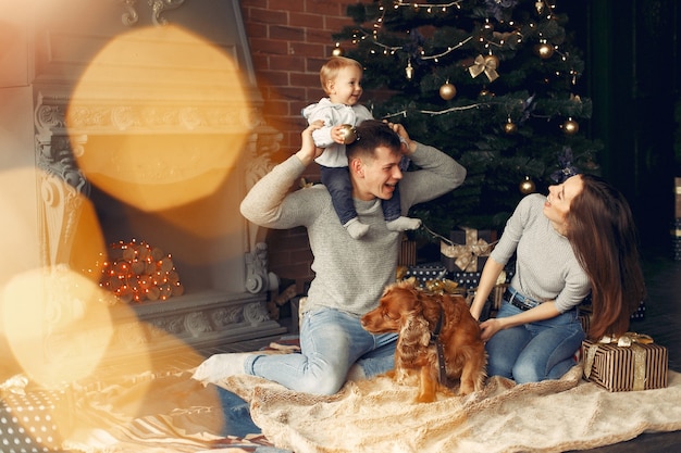 Familia con lindo perro en casa cerca del árbol de Navidad