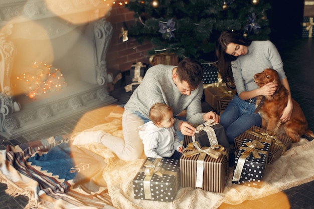 Familia con lindo perro en casa cerca del árbol de Navidad