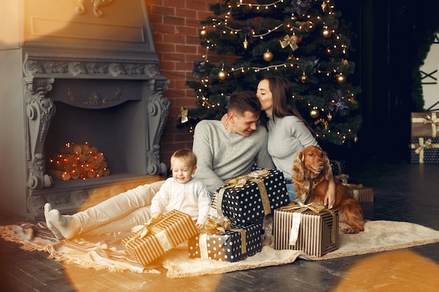 Familia con lindo perro en casa cerca del árbol de Navidad