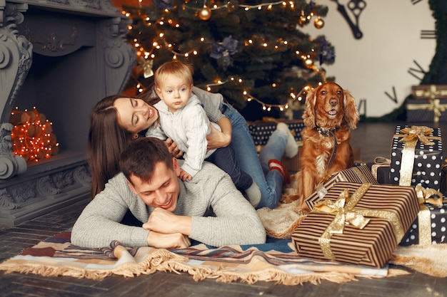 Familia con lindo perro en casa cerca del árbol de Navidad