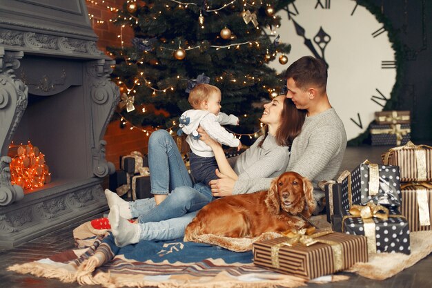 Familia con lindo perro en casa cerca del árbol de Navidad