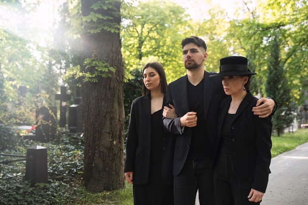 Familia de luto vestida de negro visitando el cementerio