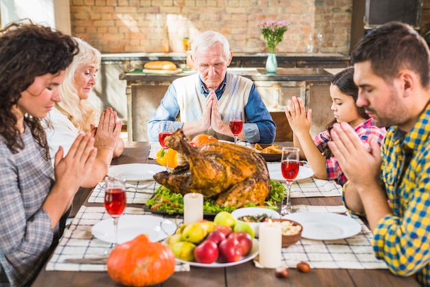 Familia en la mesa rezando antes de las comidas