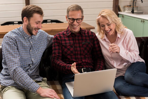 Familia mirando la computadora portátil en el sofá