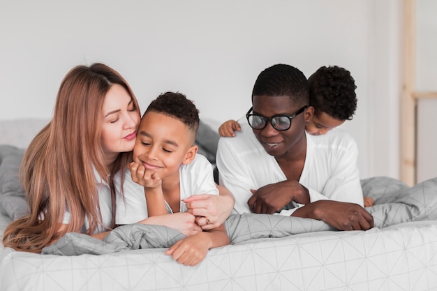 Familia multicultural feliz quedándose en la cama