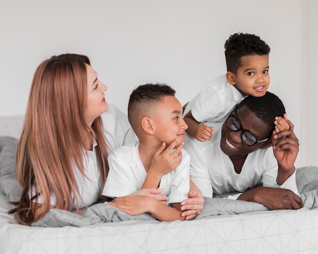 Familia multicultural feliz quedándose juntos en la cama