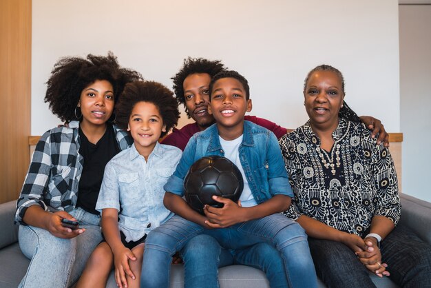 Familia multigeneración viendo partido de fútbol en casa.