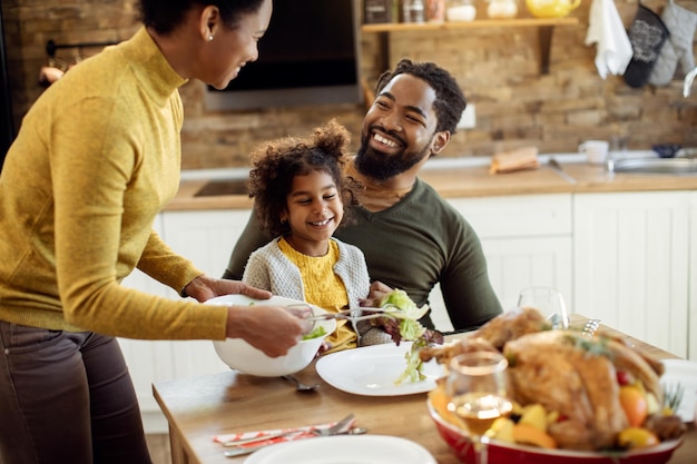 Familia negra feliz almorzando el Día de Acción de Gracias en la mesa de comedor