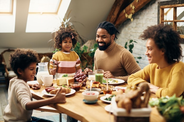 Familia negra feliz disfrutando de la comida en la mesa de comedor en casa