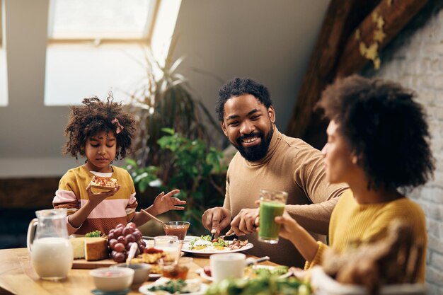 Familia negra feliz hablando mientras desayuna en casa