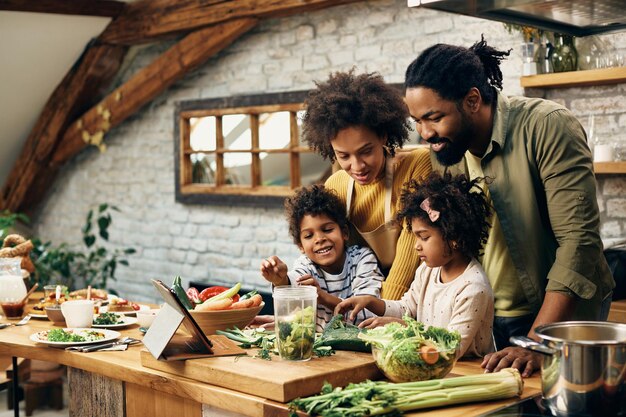 Familia negra feliz preparando comida saludable en la cocina