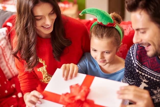 Familia con niña abriendo regalo de Navidad