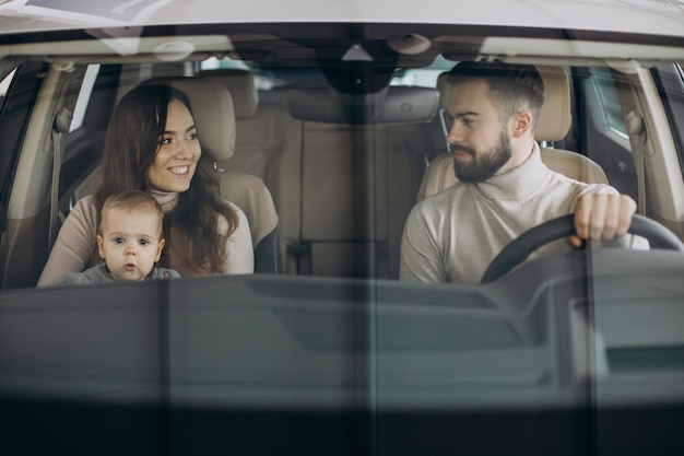 Familia con niña bbay eligiendo un coche en una berlina.