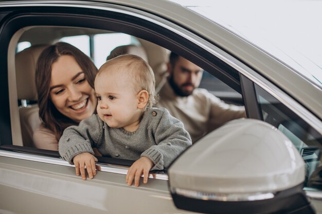 Familia con niña bbay eligiendo un coche en una berlina.