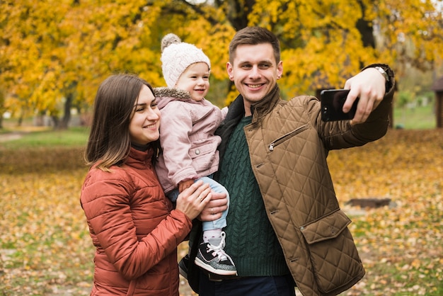 Familia en el parque de otoño haciendo selfie