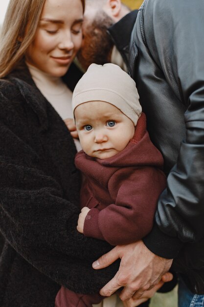 Familia en un parque de otoño. Hombre con chaqueta negra. Niña linda con sus padres.