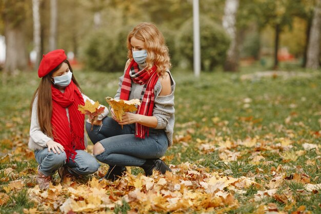 Familia en un parque de otoño. Tema de coronavirus. Madre con hija.