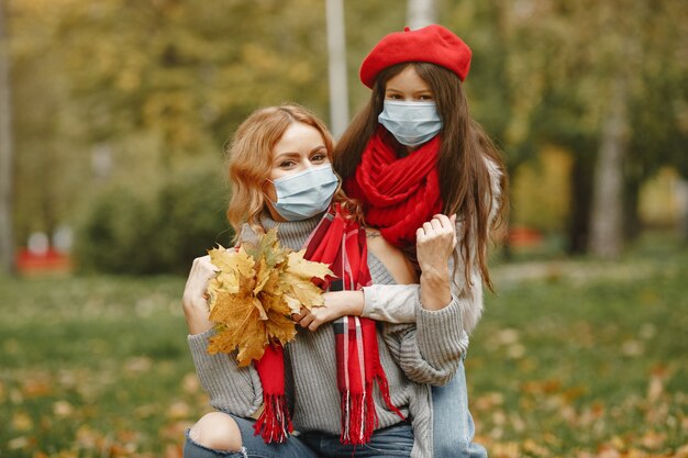 Familia en un parque de otoño. Tema de coronavirus. Madre con hija.