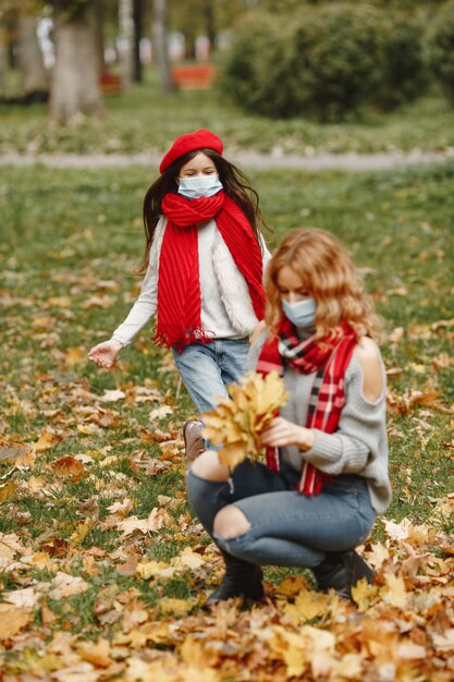 Familia en un parque de otoño. Tema de coronavirus. Madre con hija.