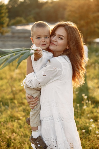 Familia en un parque de verano. Madre con un vestido blanco. Niño lindo