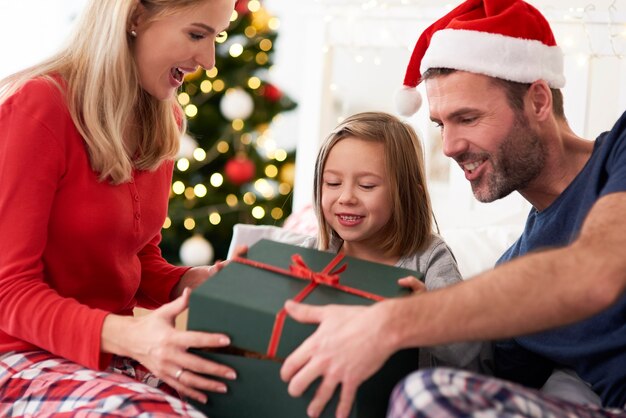 Familia a partir de Navidad abriendo regalos en la cama