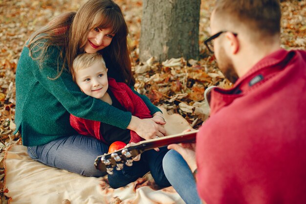 Familia con pequeño hijo en un parque de otoño