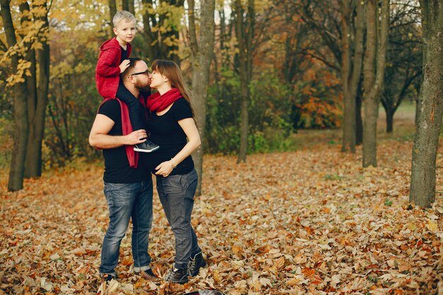 Familia con pequeño hijo en un parque de otoño