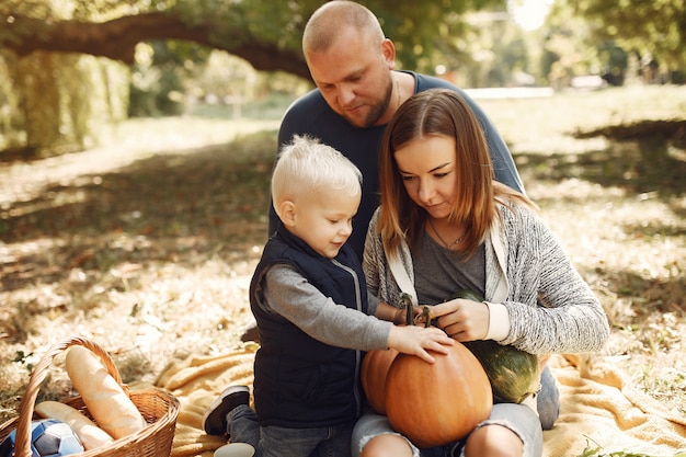 Familia con pequeño hijo en un parque de otoño