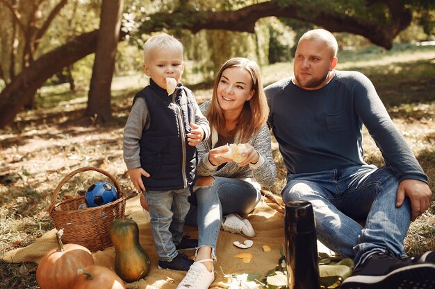 Familia con pequeño hijo en un parque de otoño