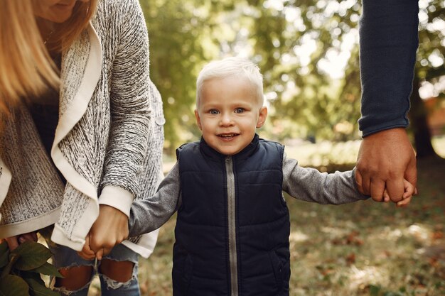 Familia con pequeño hijo en un parque de otoño