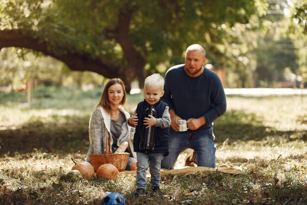 Familia con pequeño hijo en un parque de otoño