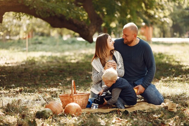 Familia con pequeño hijo en un parque de otoño