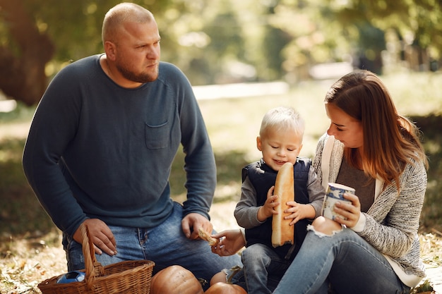 Familia con pequeño hijo en un parque de otoño