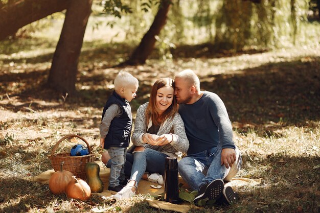 Familia con pequeño hijo en un parque de otoño