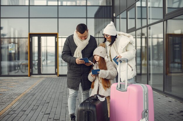 Familia de pie al aire libre con equipaje y comprobando pasaportes