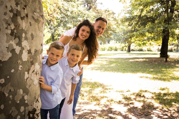 Familia posando para la cámara detrás de un árbol