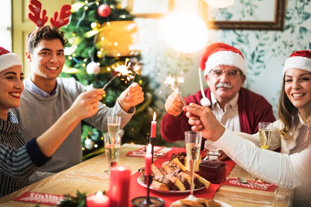 Familia con quema de fuegos de Bengala en mesa festiva