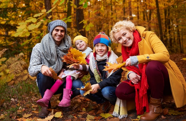 Familia recogiendo hojas en la temporada de otoño.