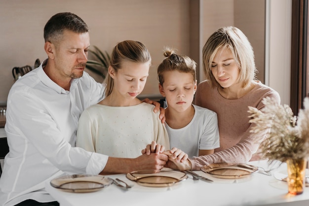 Familia rezando mientras mantiene sus manos juntas