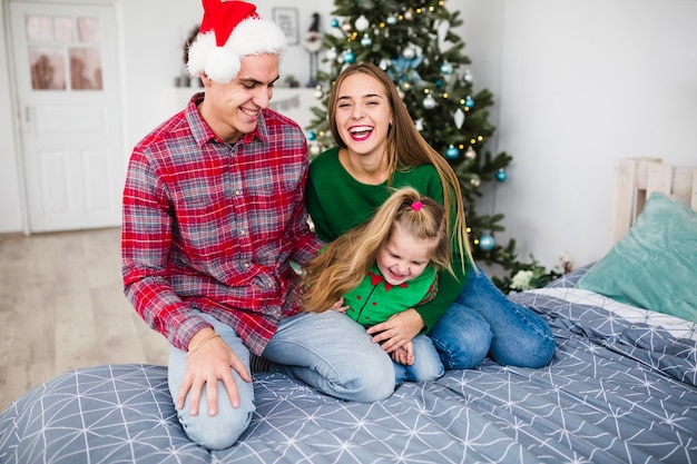 Familia riendo en la cama en navidad