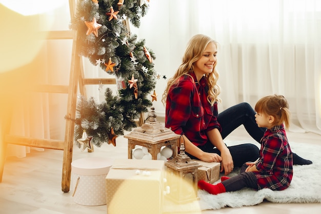 Familia sentada en casa cerca del árbol de navidad